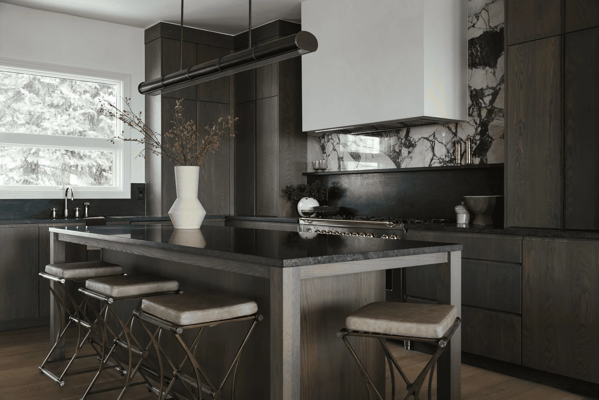 Dark oak kitchen with a sculptural stone island and dramatic marble backsplash