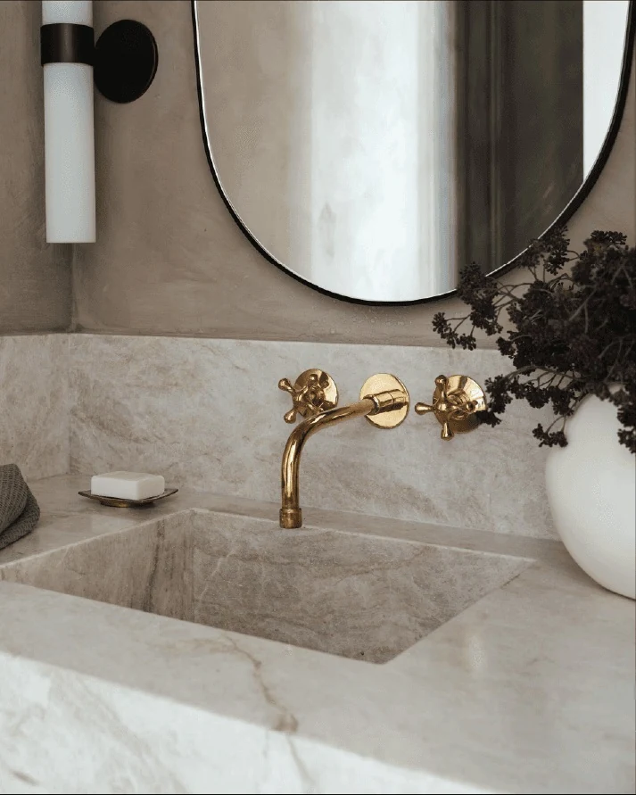 Carved stone vanity and brass wall-mounted faucet