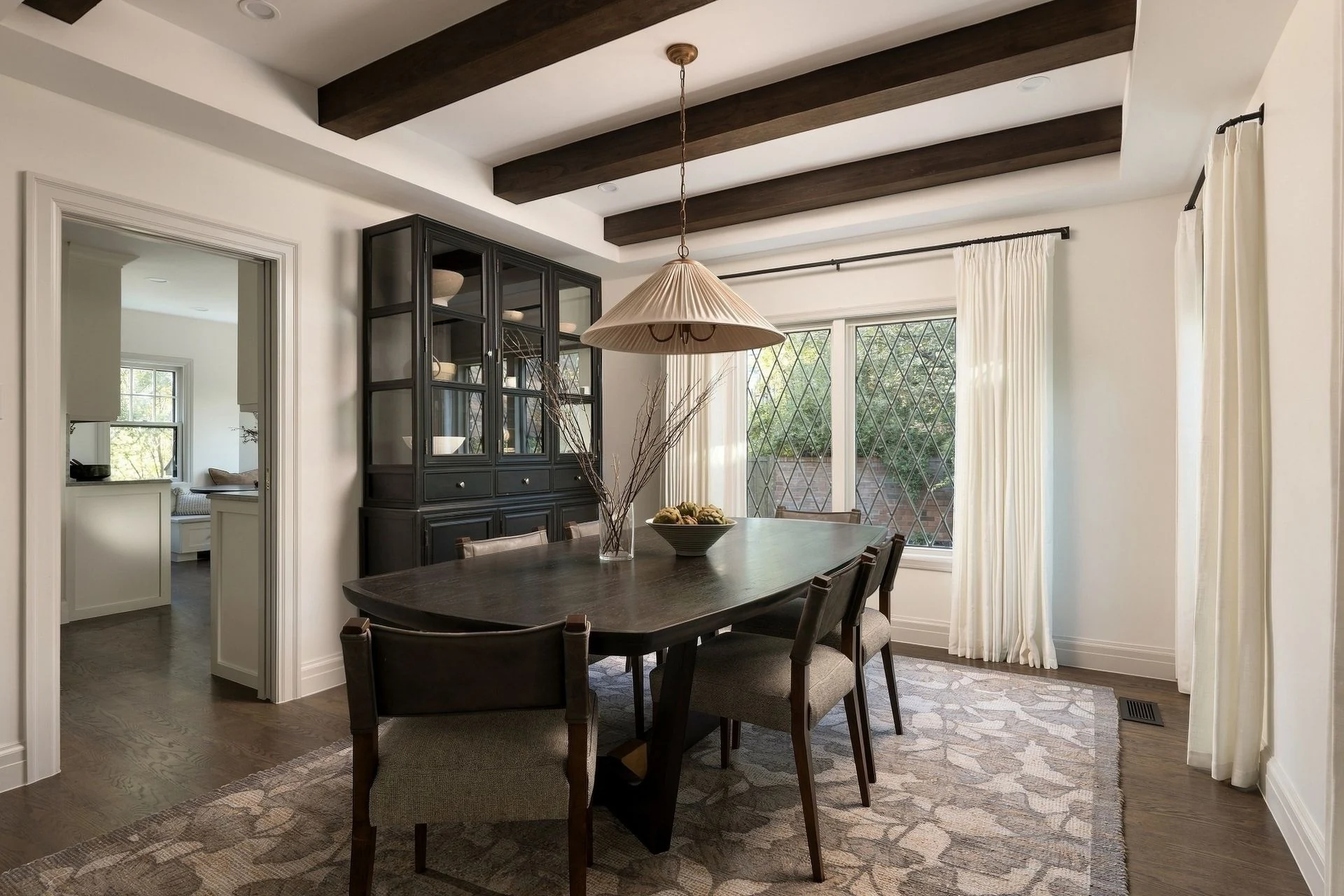 Formal dining room with exposed beams and diamond-grid windows